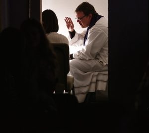 man wearing white bathrobe sitting on bed