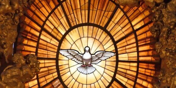 Intricate stained glass window depicting the Holy Spirit as a dove, located in St. Peter's Basilica.