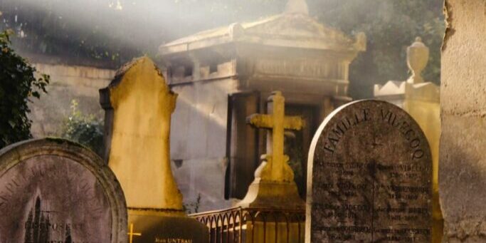 Sunbeam illuminates ancient tombstones in a serene cemetery setting.