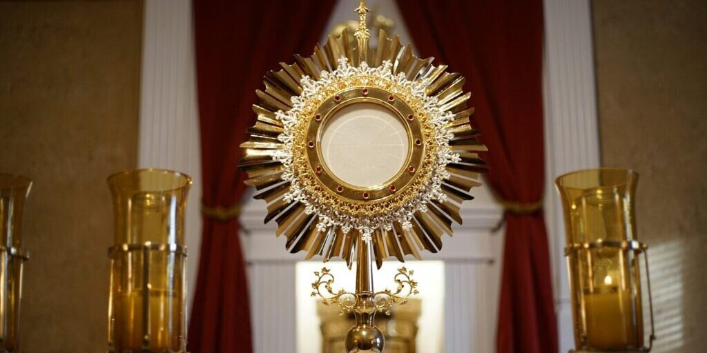 a golden cross and two candles in front of a window
